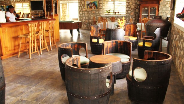 A bar area with wooden bar stools, a pool table, and a stone wall with windows.