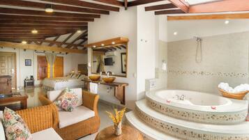 A bathroom with a large bathtub, a sink, and a shower. There is a wicker chair and a wicker ottoman in the room.