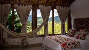 A room with a bed, a hammock, and large windows with curtains. - Hotel Spa La Colina (Pereira)