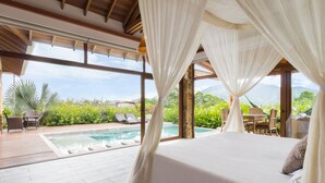 A bedroom with a large window, a pool, and outdoor furniture. - Hotel Spa La Colina (Pereira)