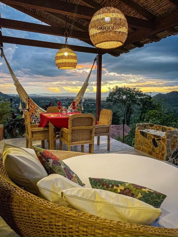 A cozy outdoor seating area with wicker furniture, a table with red tablecloth, and hanging wicker lamps. - Hotel Spa La Colina (Pereira)