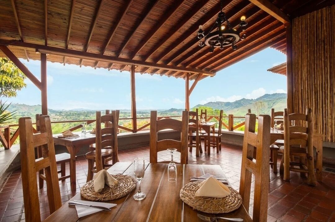 A wooden dining area with tables and chairs, overlooking a scenic landscape.