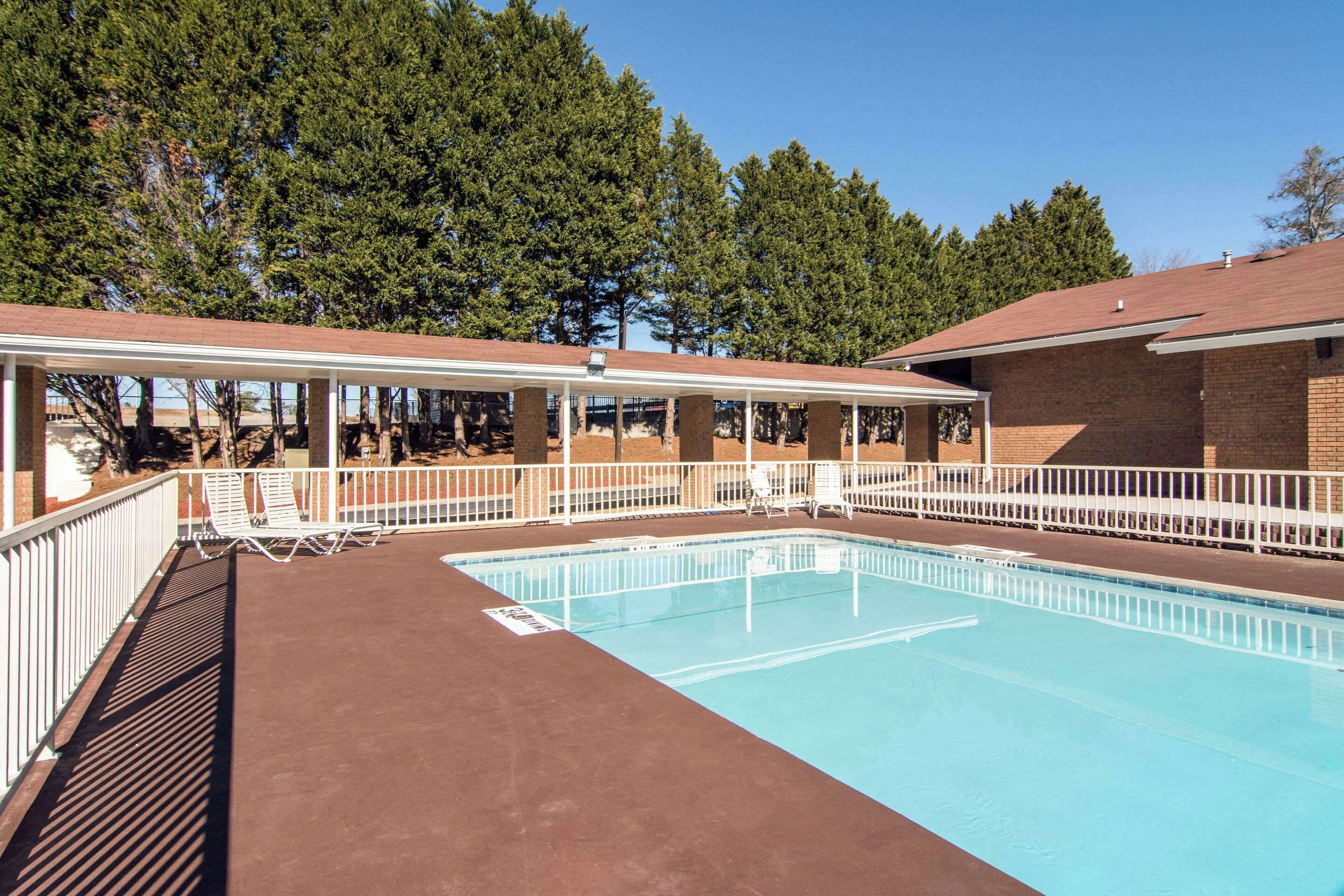 A rectangular swimming pool with a covered area and lounge chairs.