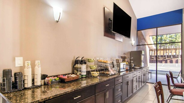A modern kitchen area with a granite countertop, stainless steel appliances, and a flat-screen TV mounted on the wall. - Quality Inn Toccoa (Toccoa)