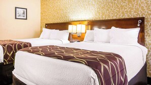 A hotel room with two beds, a patterned wallpaper, a framed picture on the wall, and a nightstand with a lamp. - Quality Inn Toccoa (Toccoa)