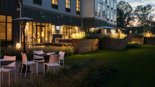 Un hotel con varios pisos, zona de estar al aire libre y una entrada bien iluminada.