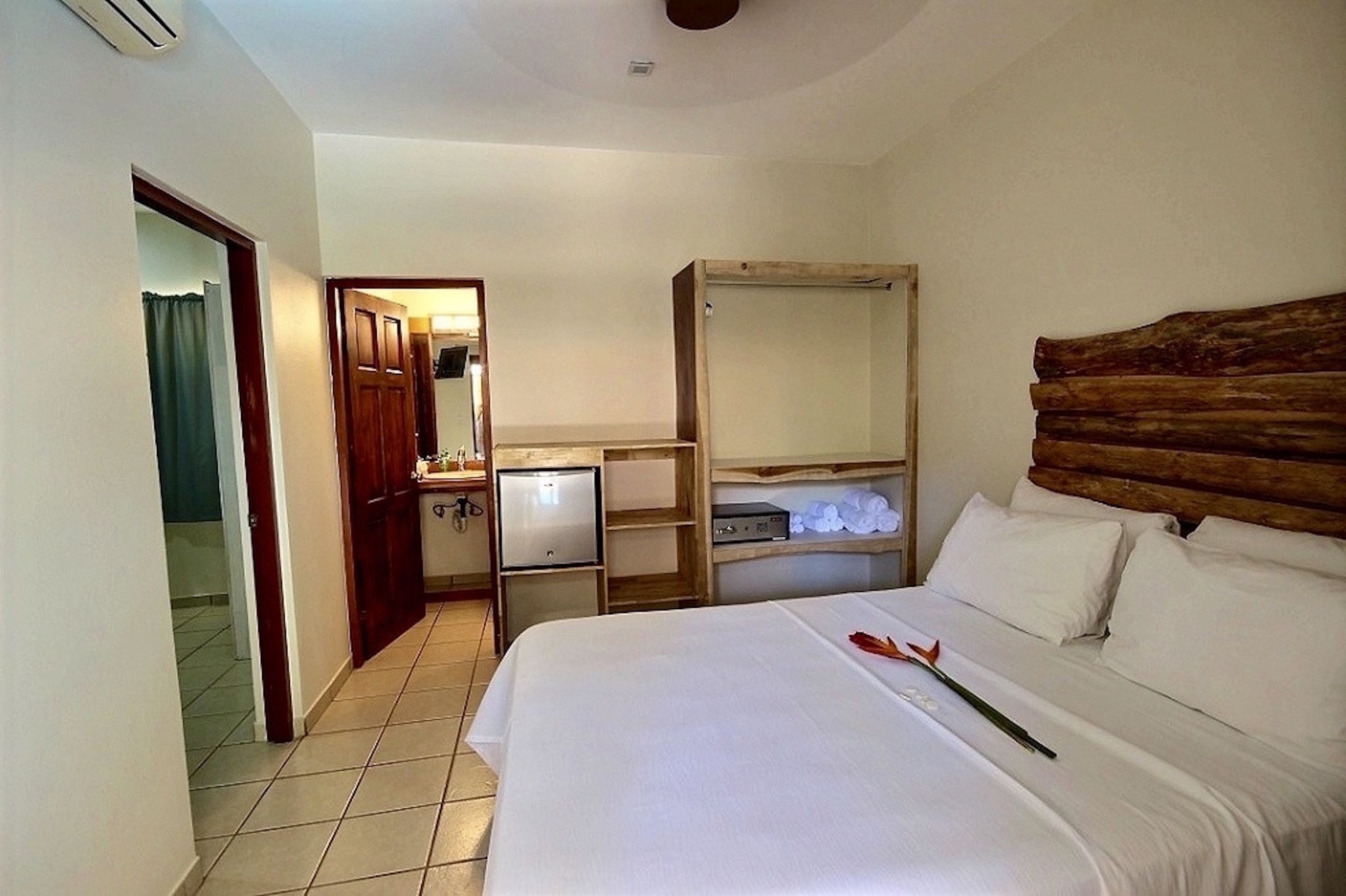 A hotel room with a bed, a wooden headboard, a small desk with a computer, and a wardrobe.