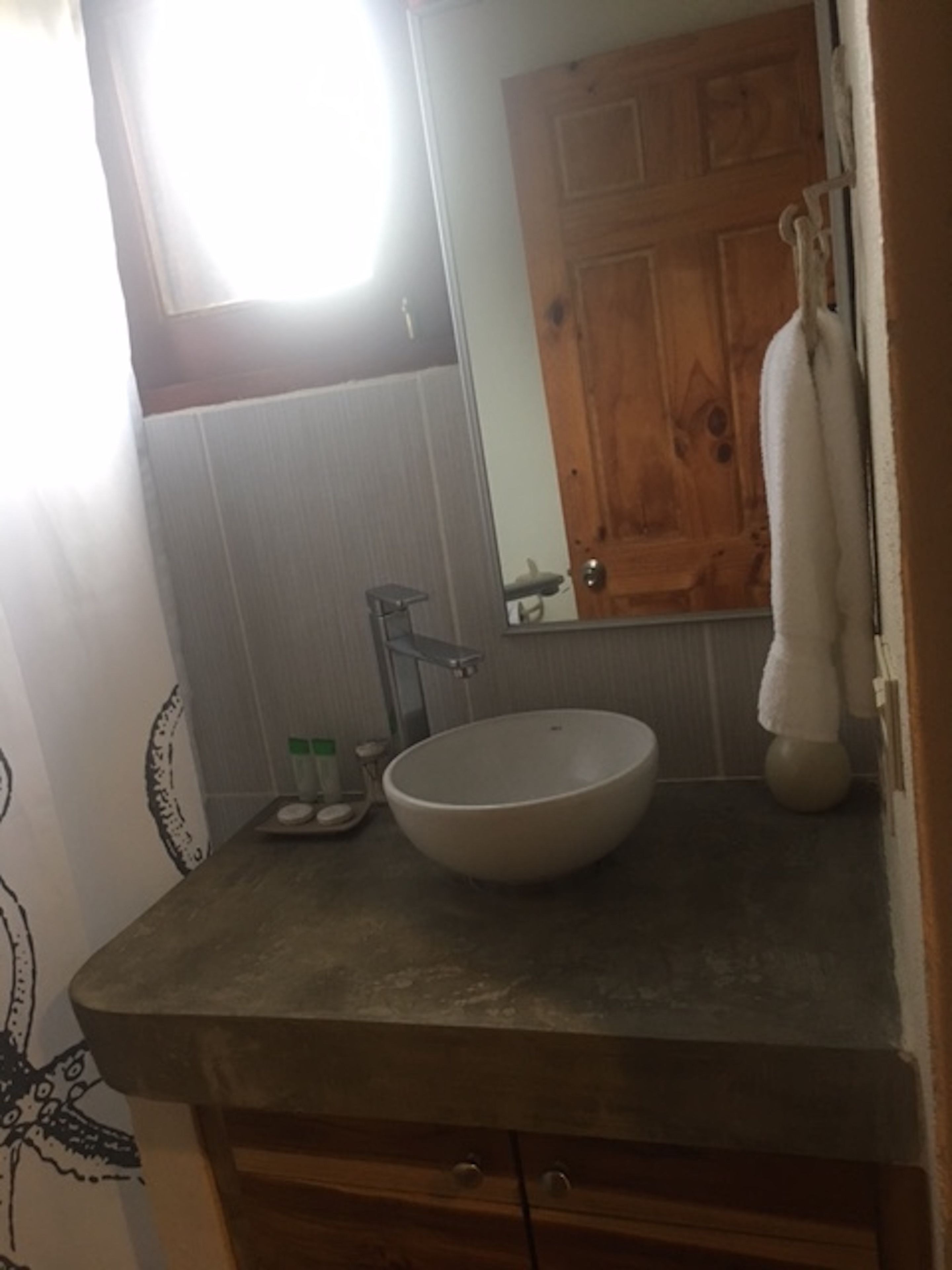 Un baño con tocador de madera, un espejo grande, un lavamanos y una toalla colgada en la pared.