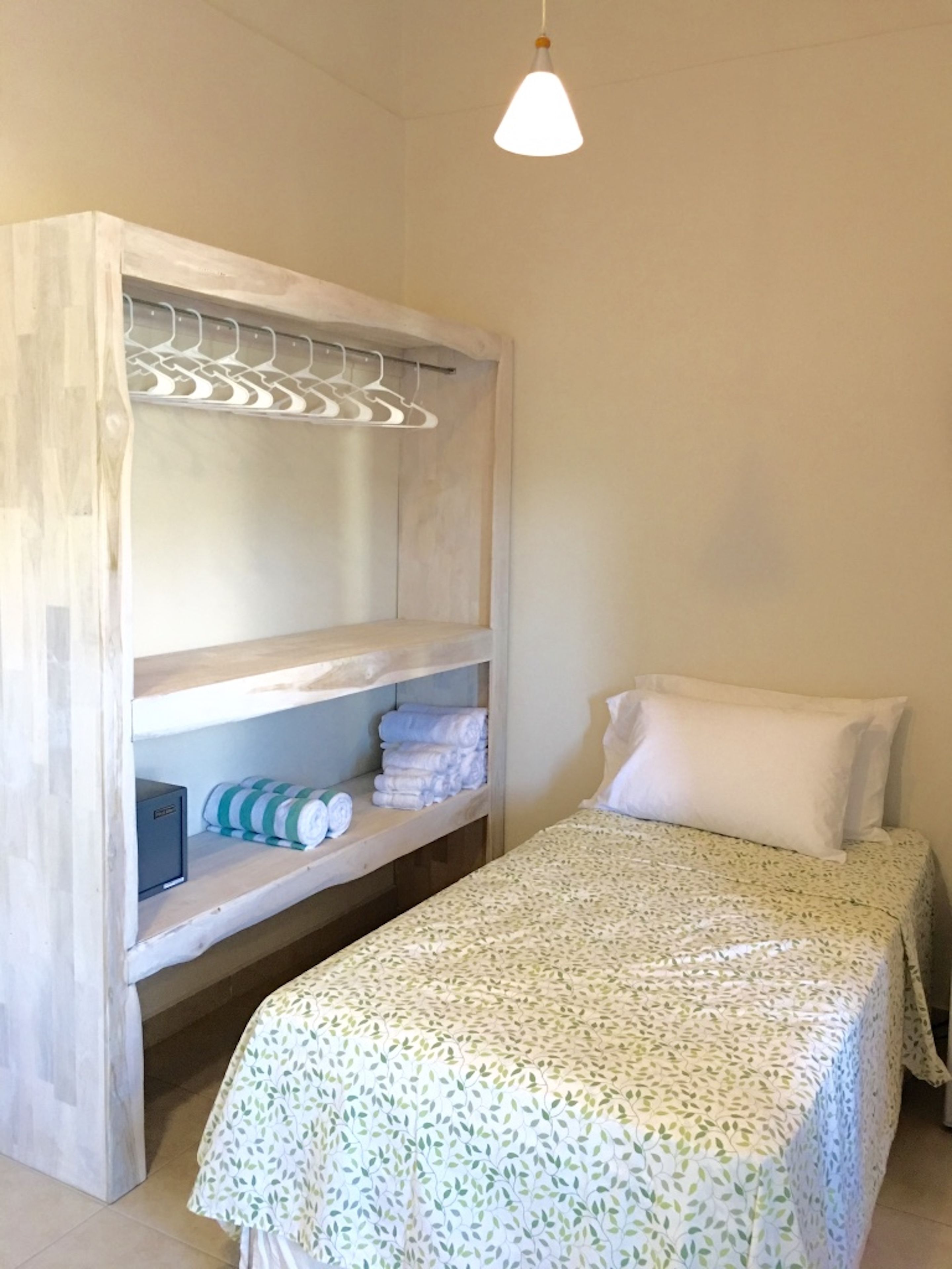 A bedroom with a bed, a wardrobe with hanging space, and a bedside table.