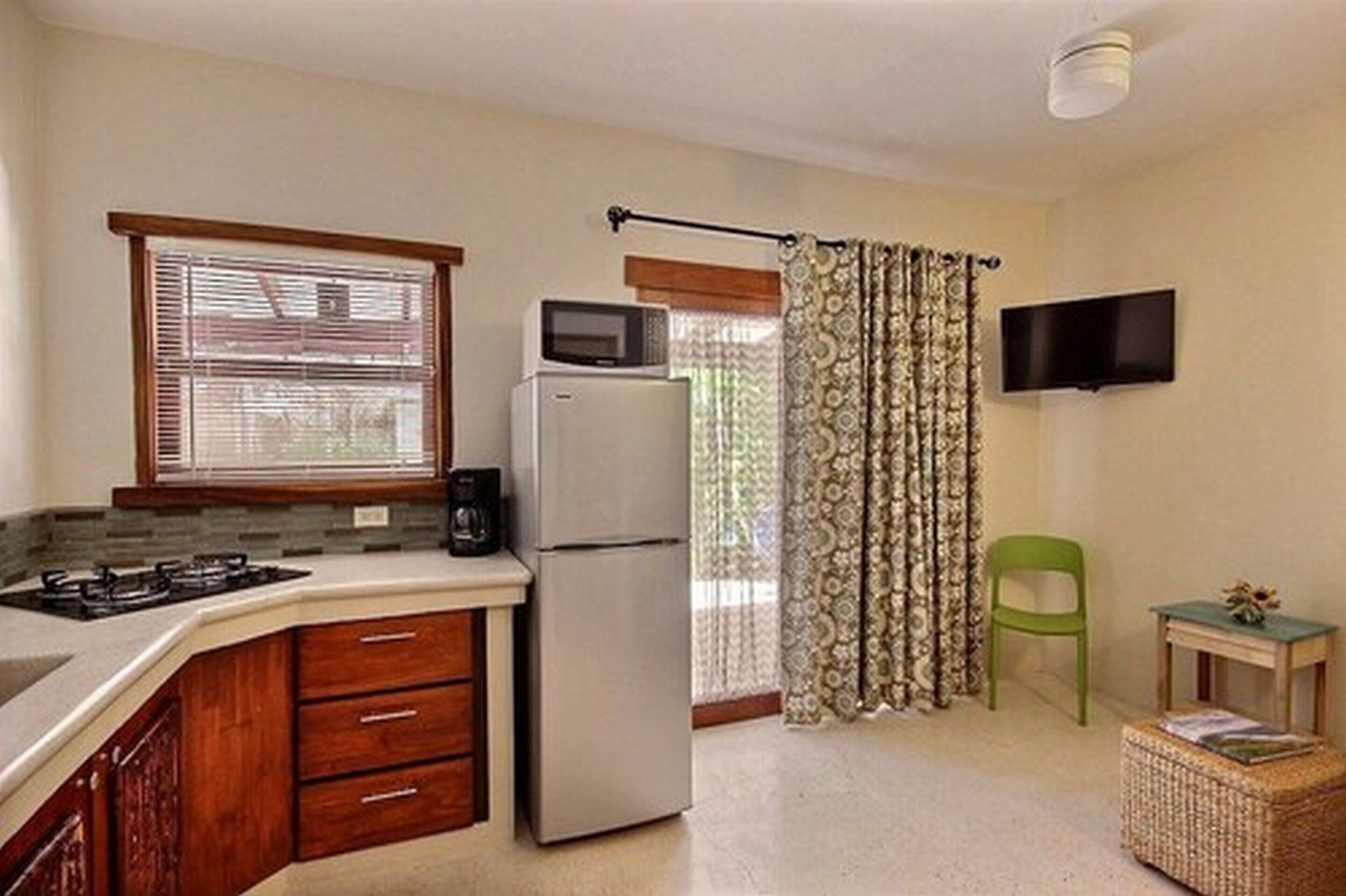 A compact kitchen with a refrigerator, microwave, and gas stove. There is a small dining area with a chair and a table.