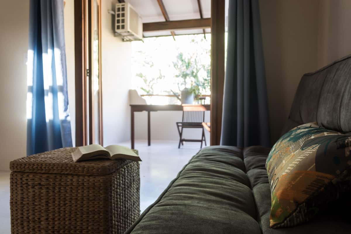 Ein gemütliches Wohnzimmer mit einer Couch, einem Korbsessel und einem Tisch mit einem Stuhl.