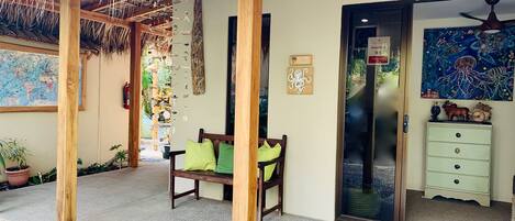 A wooden bench with green cushions, a thatched roof, a map on the wall, and a decorative octopus sign.