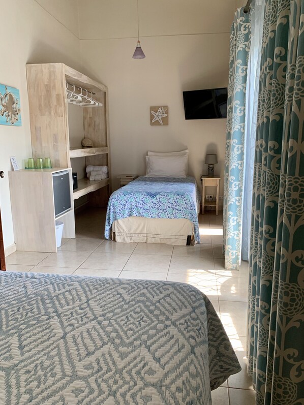 Ein Schlafzimmer mit Bett, Kleiderschrank, Schreibtisch und Fernseher.