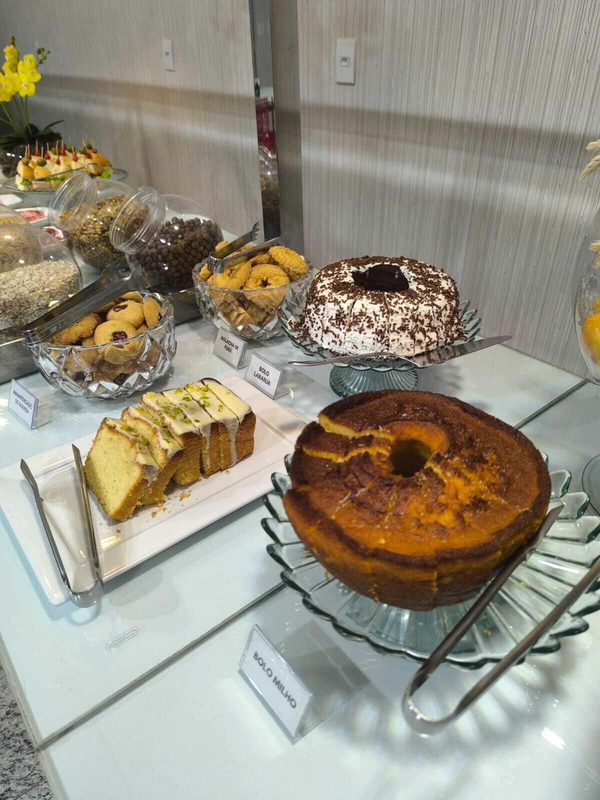 A buffet with various desserts and snacks, including a bundt cake and a cake with white frosting and chocolate shavings.