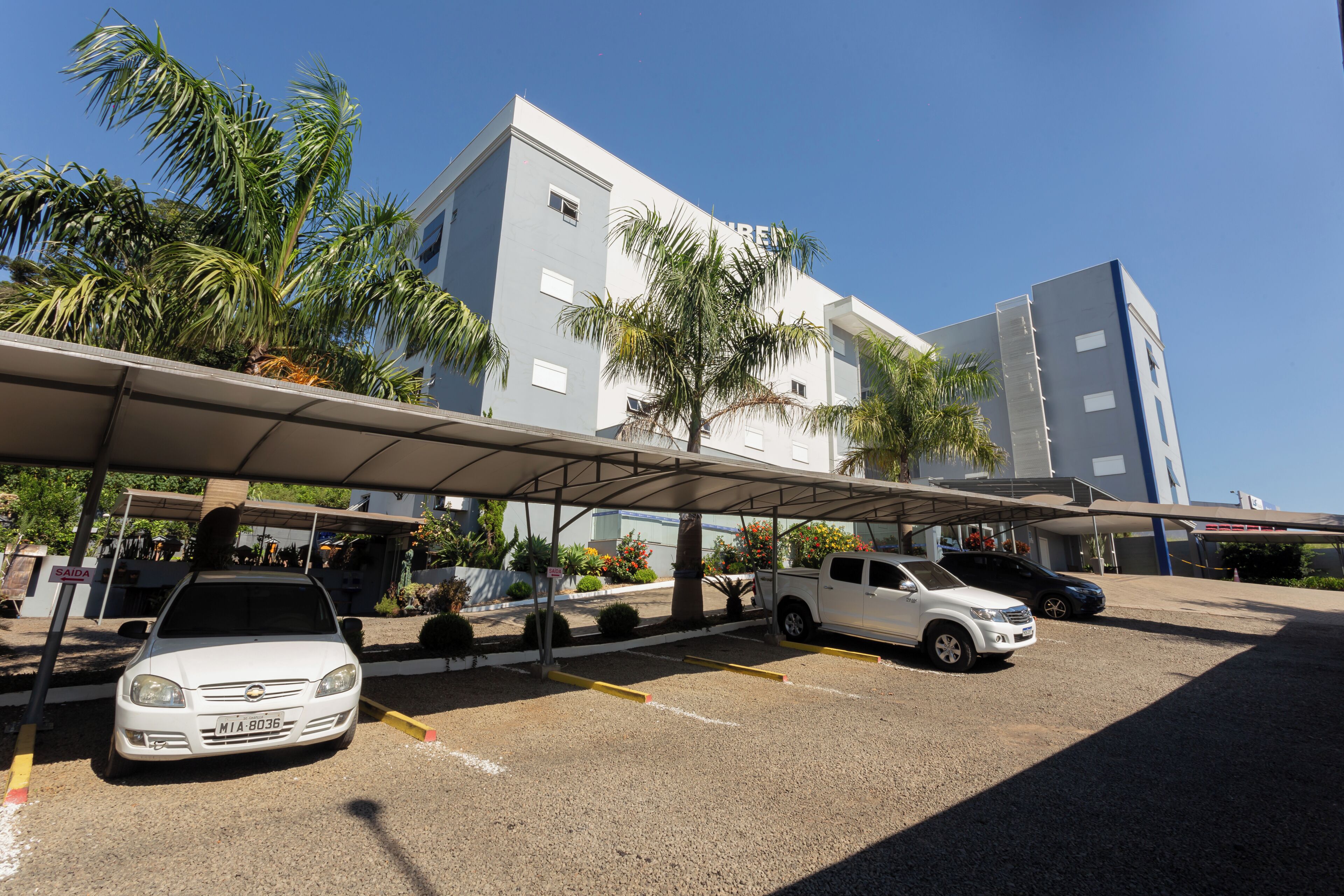 A parking area with a covered structure, a white car, and a building with 'RENTAL' signage.