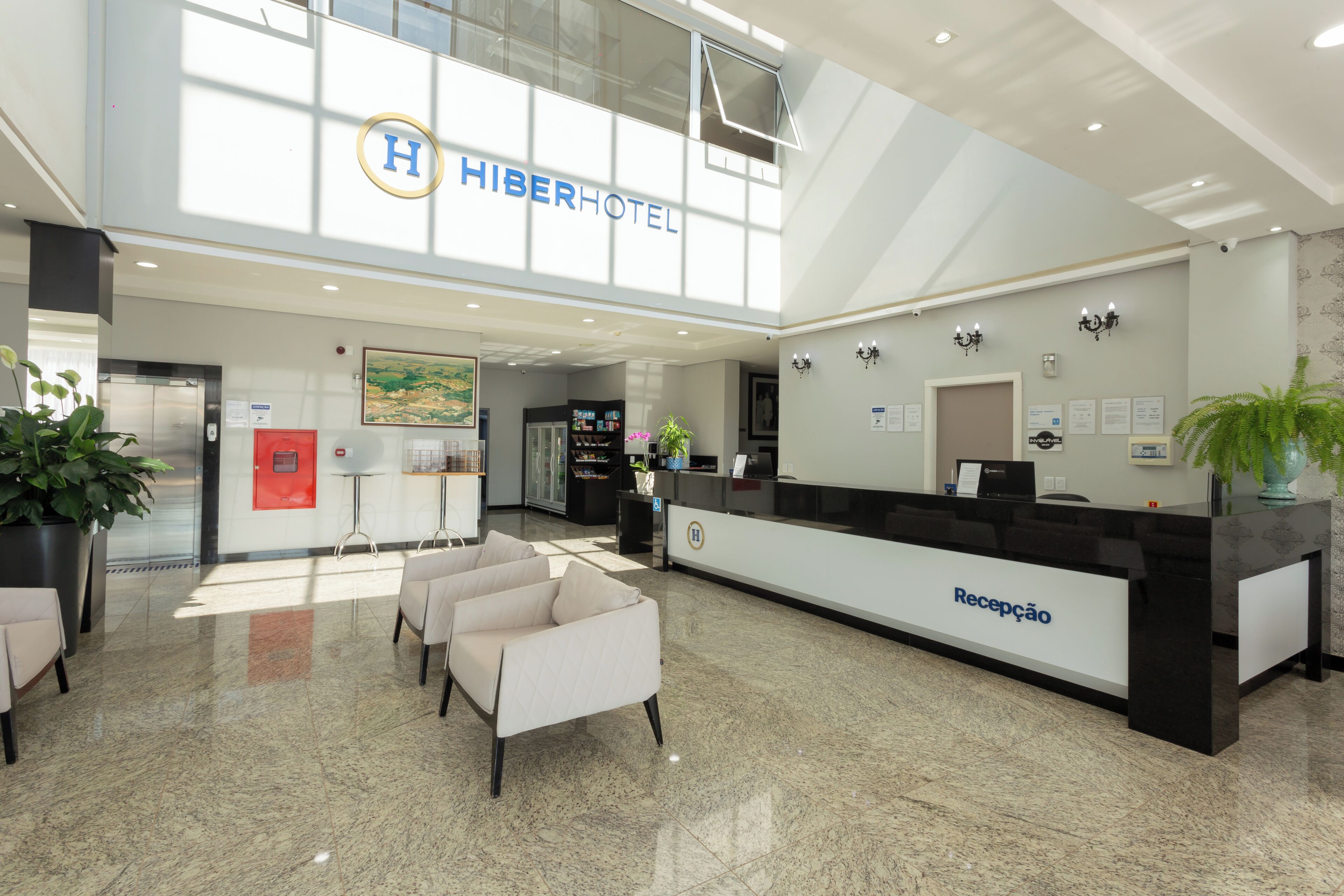 A hotel reception area with a modern design, a reception desk, seating area, and a large window providing natural light.