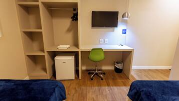 Ein Hotelzimmer mit einem Bett, einem Schreibtisch, einem Sessel, einem Fernseher und einem Kleiderschrank.