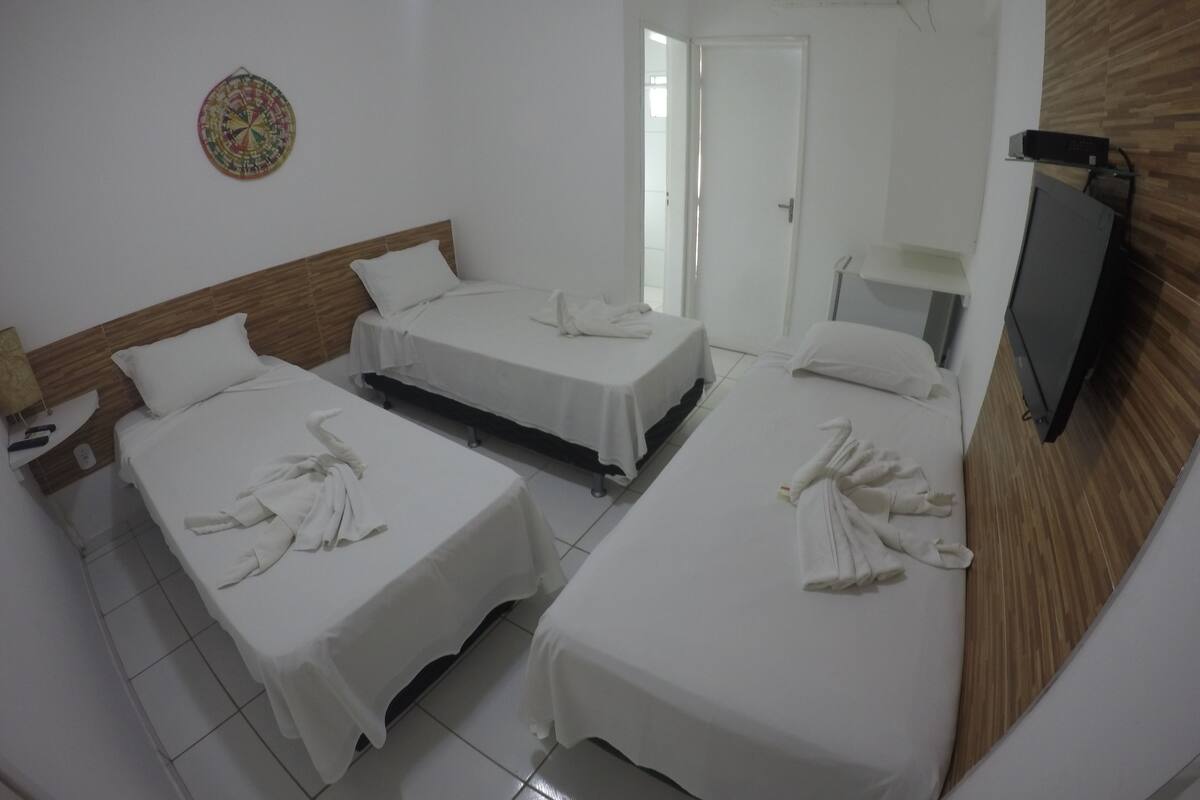 Ein Hotelzimmer mit zwei Betten, einem Fernseher und einer Wandklimaanlage.