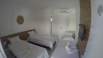 A hotel room with three single beds, a small round table, and a wall-mounted TV.