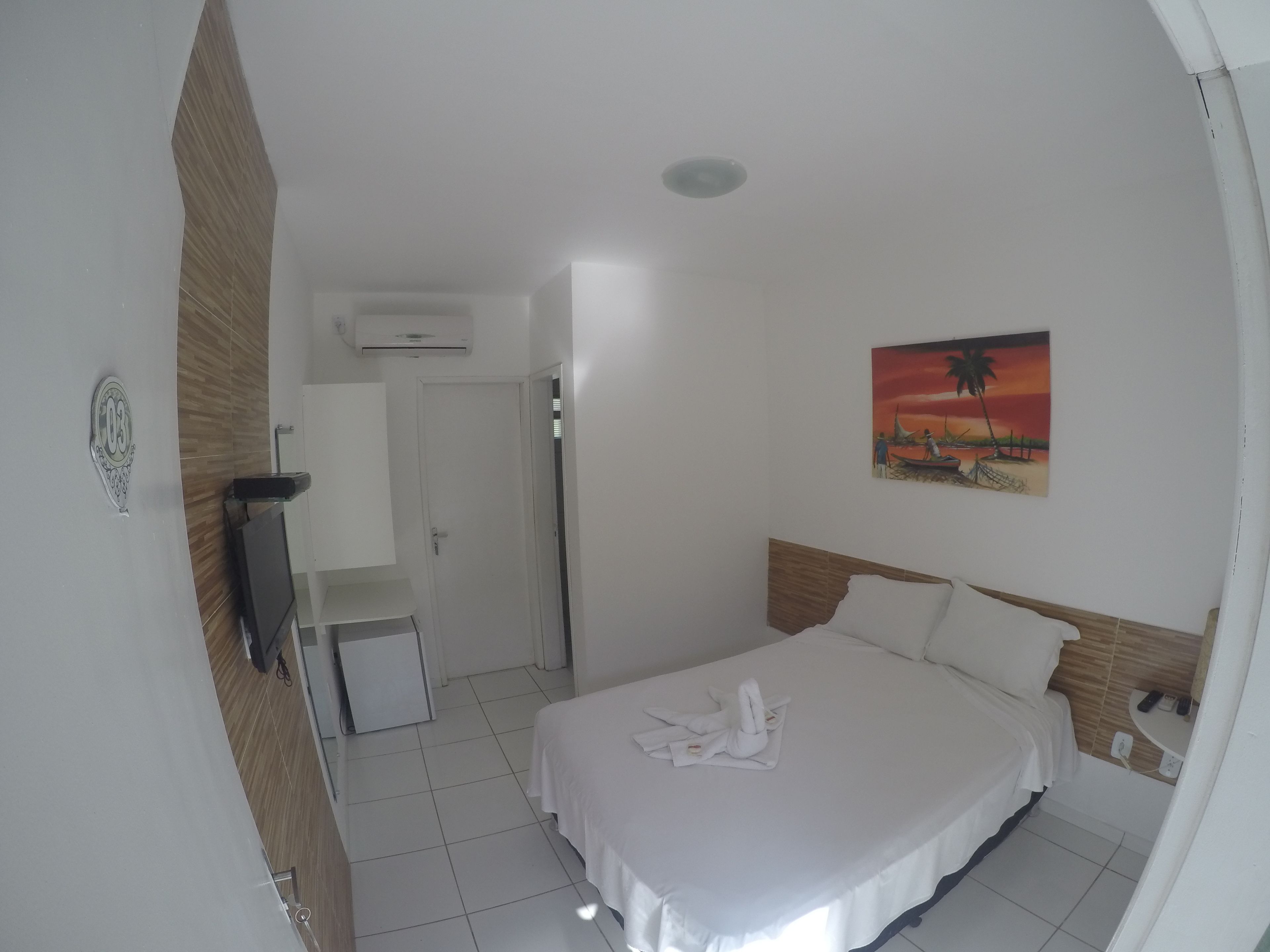 Una habitación de hotel con una cama, un cuadro, un escritorio y un equipo de aire acondicionado.