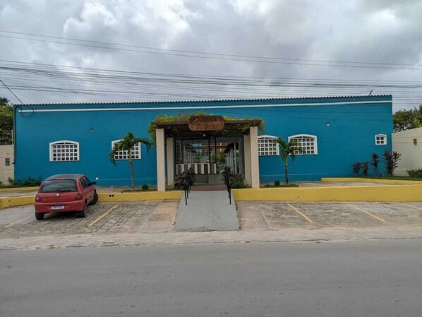 A building with a blue exterior, a covered entrance, and a red car parked in front.