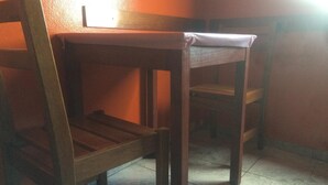 A wooden chair with a high backrest and a flat seat, positioned in a corner of a room with tiled flooring. - Hotel La Torre Butantã (São Paulo)