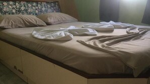 A bed with a beige mattress and pillows, a floral headboard, and a plain wall with a window. - Hotel La Torre Butantã (São Paulo)