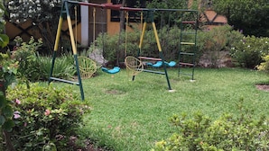 Een tuin met een schommel en een huis op de achtergrond.