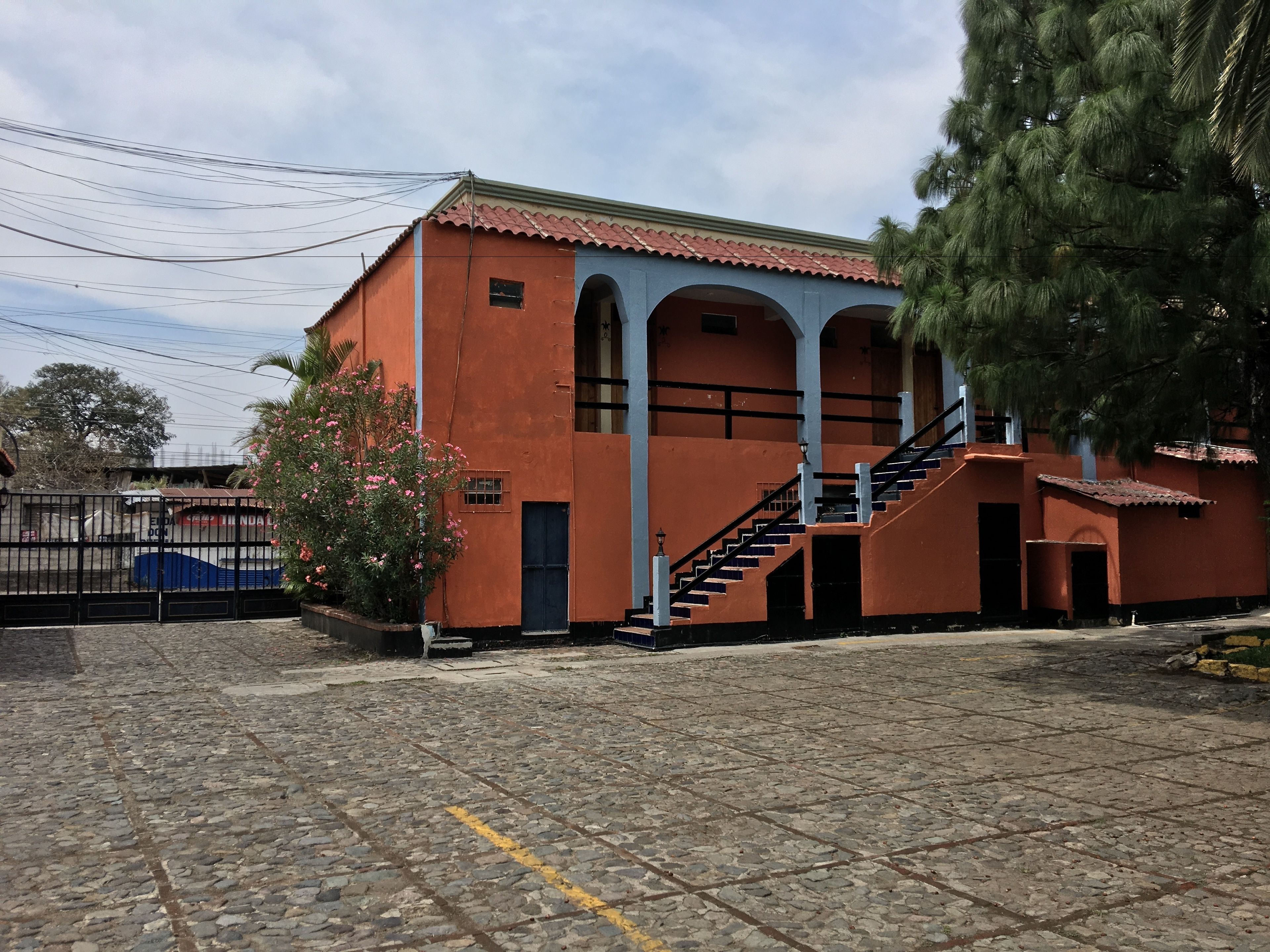 Un edificio con fachada roja, arcos azules y una escalera que conduce a la entrada.