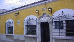 A yellow building with a black door, white window frames, and decorative metal railings.