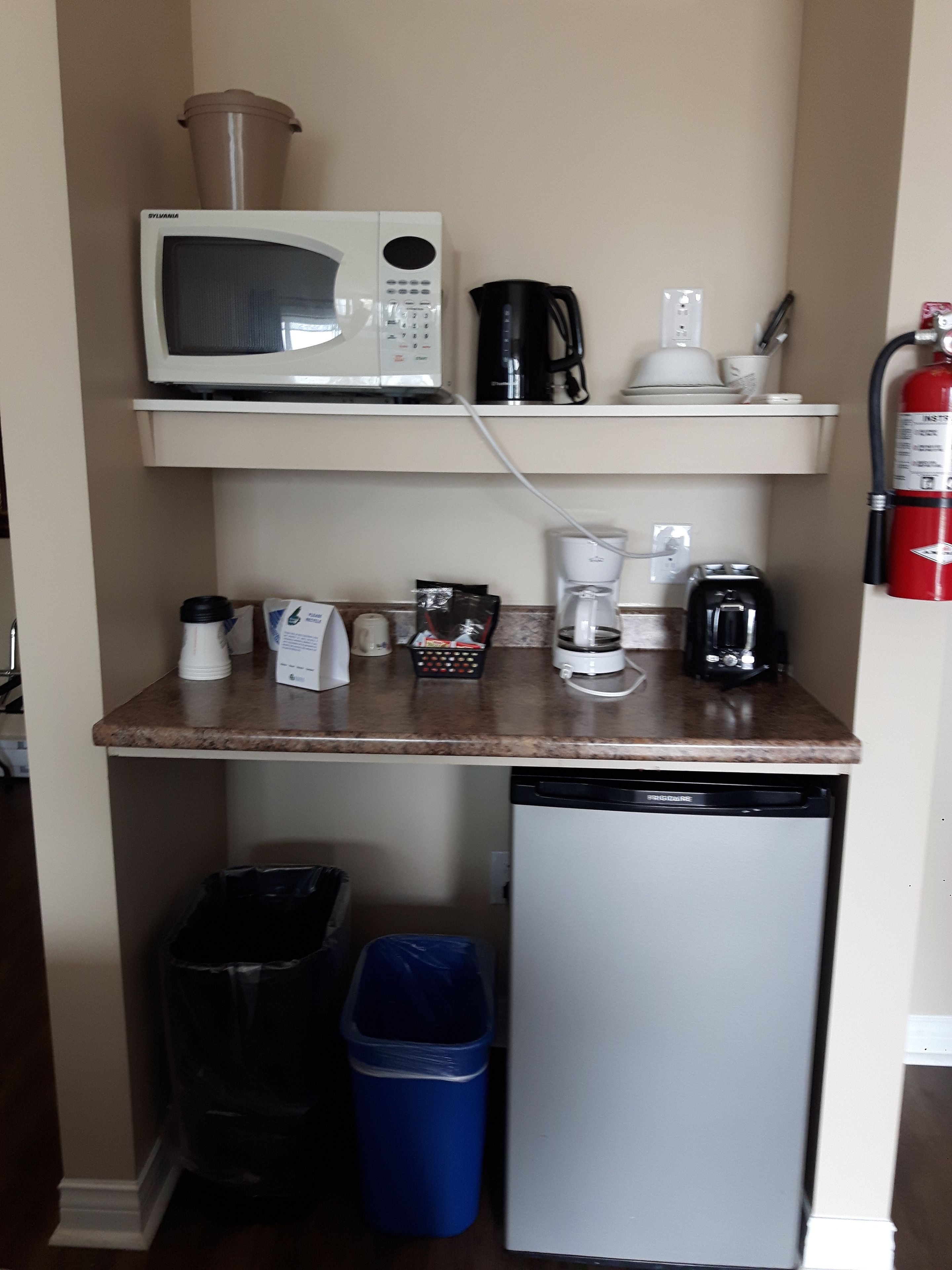 A compact kitchenette with a microwave, coffee maker, and a dishwasher.
