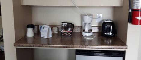Een kleine keuken met een magnetron, koffiezetapparaat en vaatwasser.