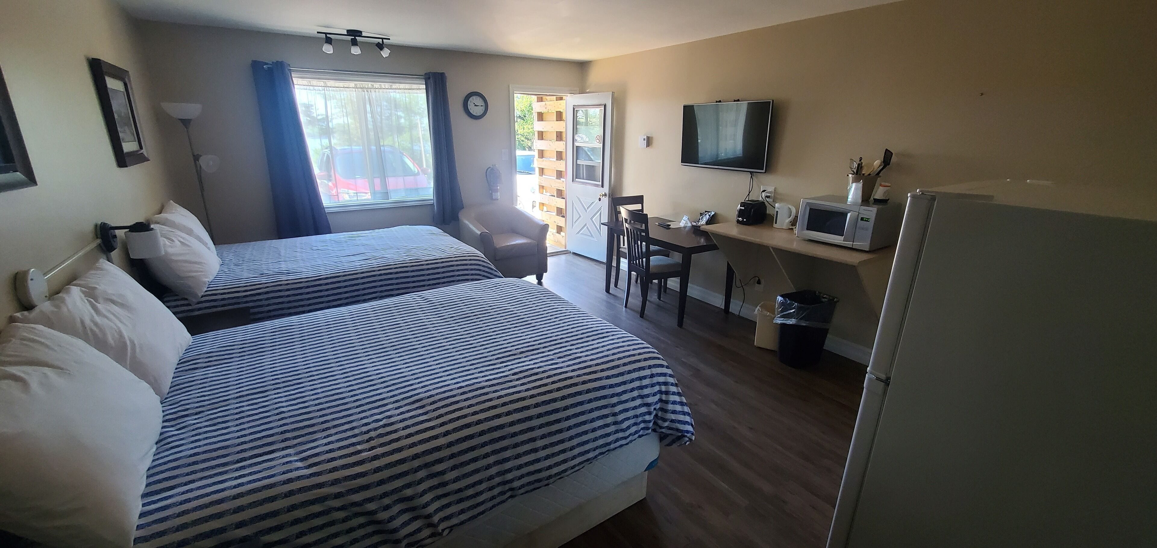 Camera d'albergo con due letti, una scrivania, una televisione e un frigorifero.