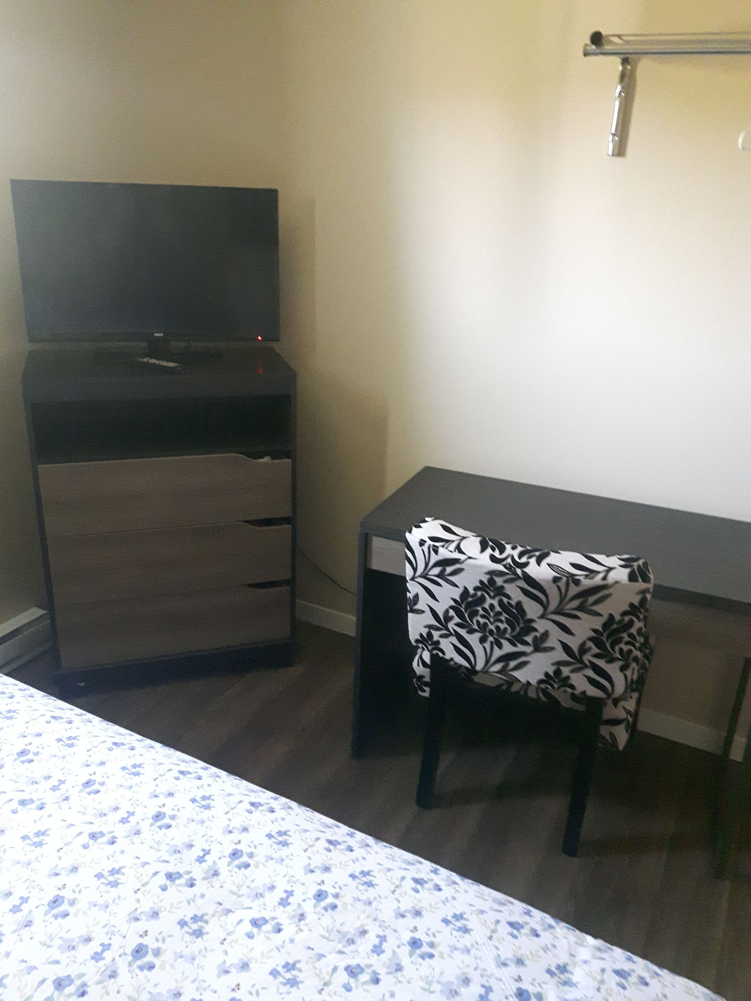 Une petite pièce comprenant un lit, un bureau et une armoire.