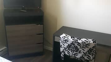 Une petite pièce comprenant un lit, un bureau et une armoire.