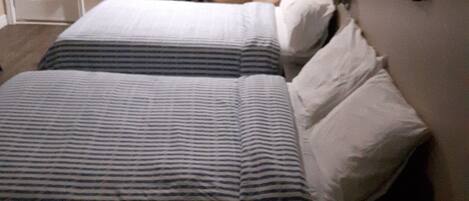 Una habitación de hotel con una cama, una silla, una mesita y una puerta.