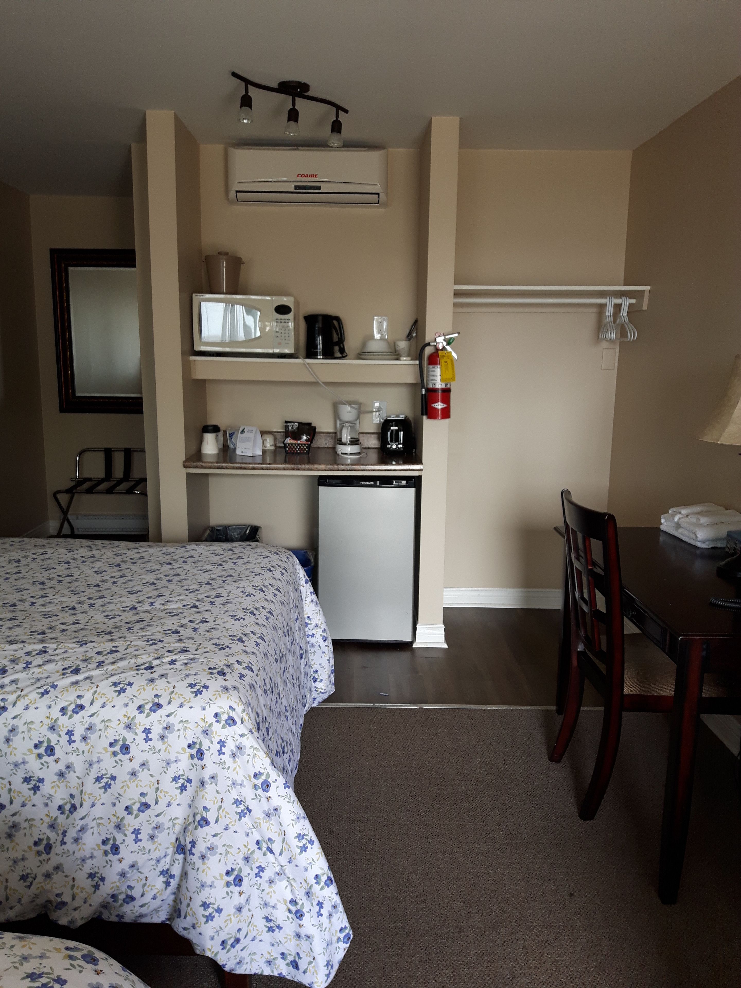 A compact hotel room with a bed, kitchenette, and a dining area.