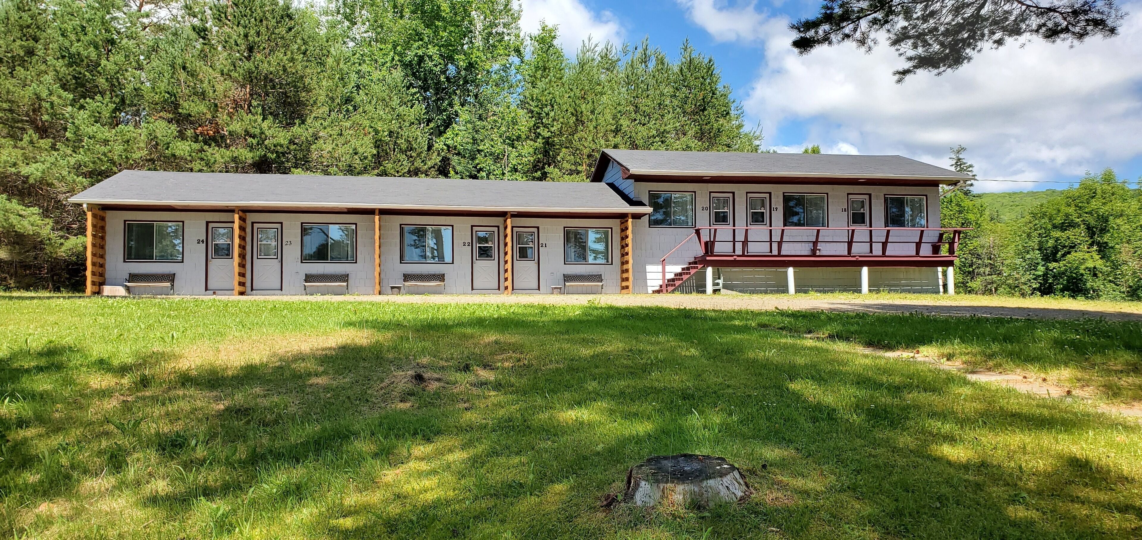 A two-story building with numbered doors, a covered porch, and a grassy yard.