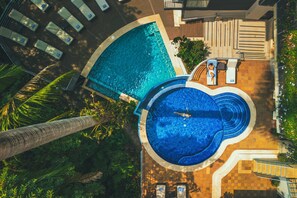 A rooftop pool with a circular design, surrounded by lounge chairs and a palm tree.