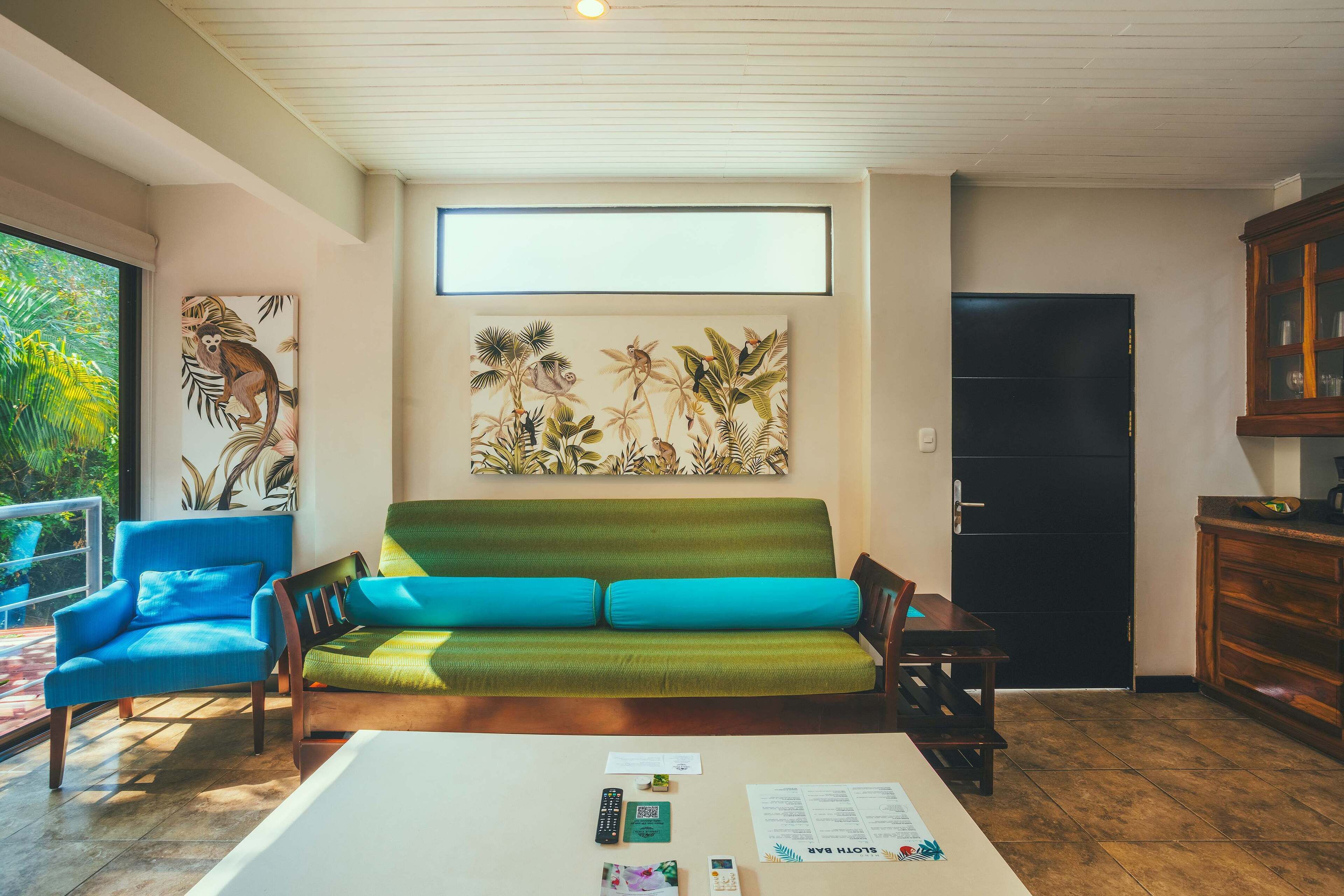 Ein Wohnzimmer mit einem grünen Sofa, einem blauen Sessel und einem Holzkabinett.