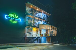Un edificio de varios pisos con un letrero de neón que dice 'Jungle Vista Boutique Hotel'.