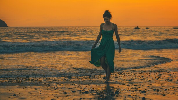 A woman in a green dress walking on a beach at sunset. - Jungle Vista Boutique Hotel (Quepos)