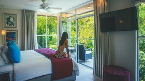 Un dormitorio con cama, televisor montado en la pared y un gran ventanal que ofrece vistas al exterior.