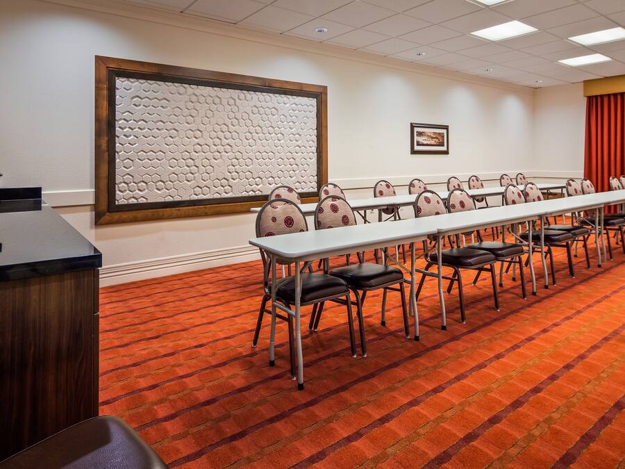 A conference room with a long table, chairs, a projector screen, and a coffee station.