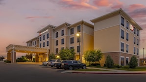 A hotel with a covered entrance, multiple floors, and a parking lot with several cars. - Best Western Plus Hudson Hotel & Suites (Hudson)