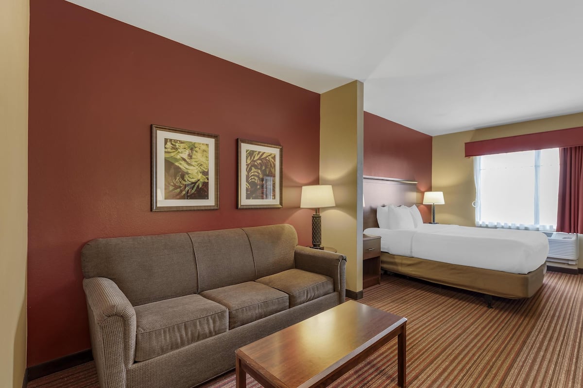 A hotel room with a sofa, two bedside tables, a bed, and two wall-mounted lamps.