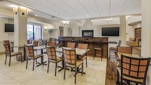 A spacious dining area with multiple tables and chairs, a counter with a flat-screen TV, and a view of the outdoors through large windows. - Best Western Plus Hudson Hotel & Suites (Hudson)