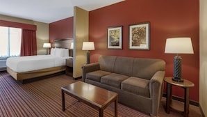 A hotel room with a bed, a sofa, a coffee table, and two lamps. - Best Western Plus Hudson Hotel & Suites (Hudson)