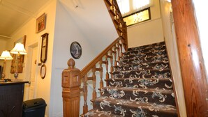 A staircase with floral carpet, wooden handrail, and a wall with framed pictures and a clock. - Perfect Stay Inn & Suites (Blair)