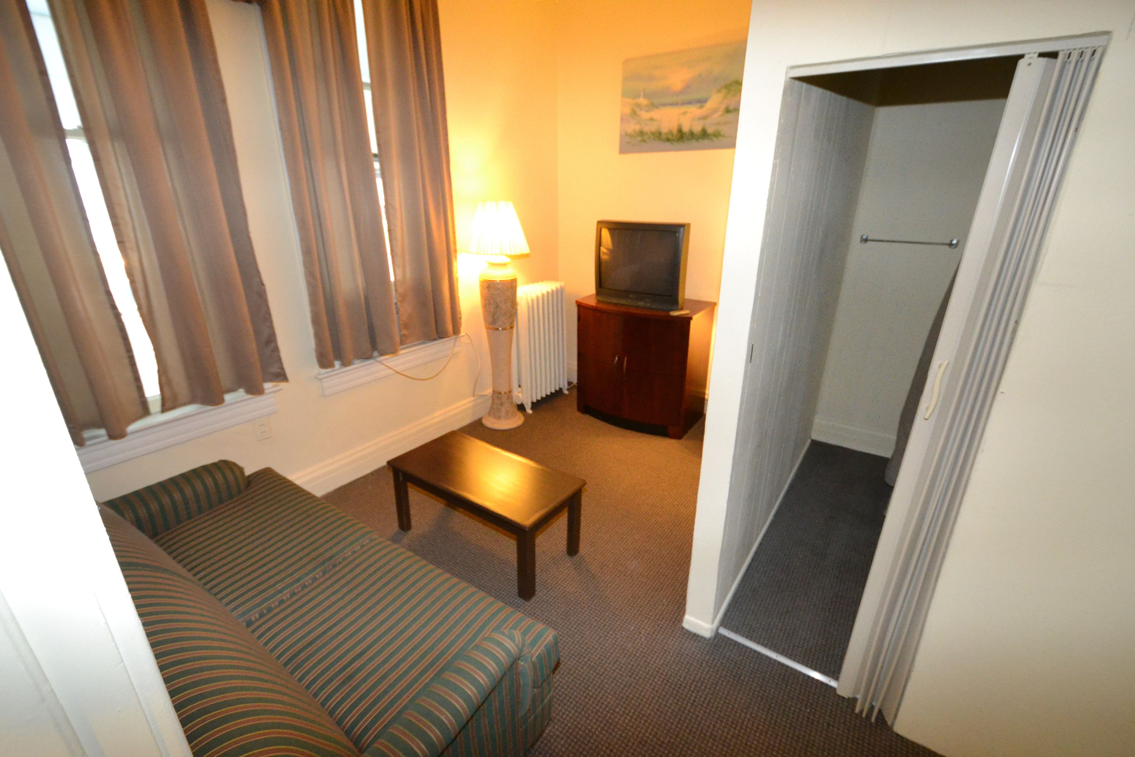 Een woonkamer met een bank, een salontafel, een lamp, een televisie en een radiator.